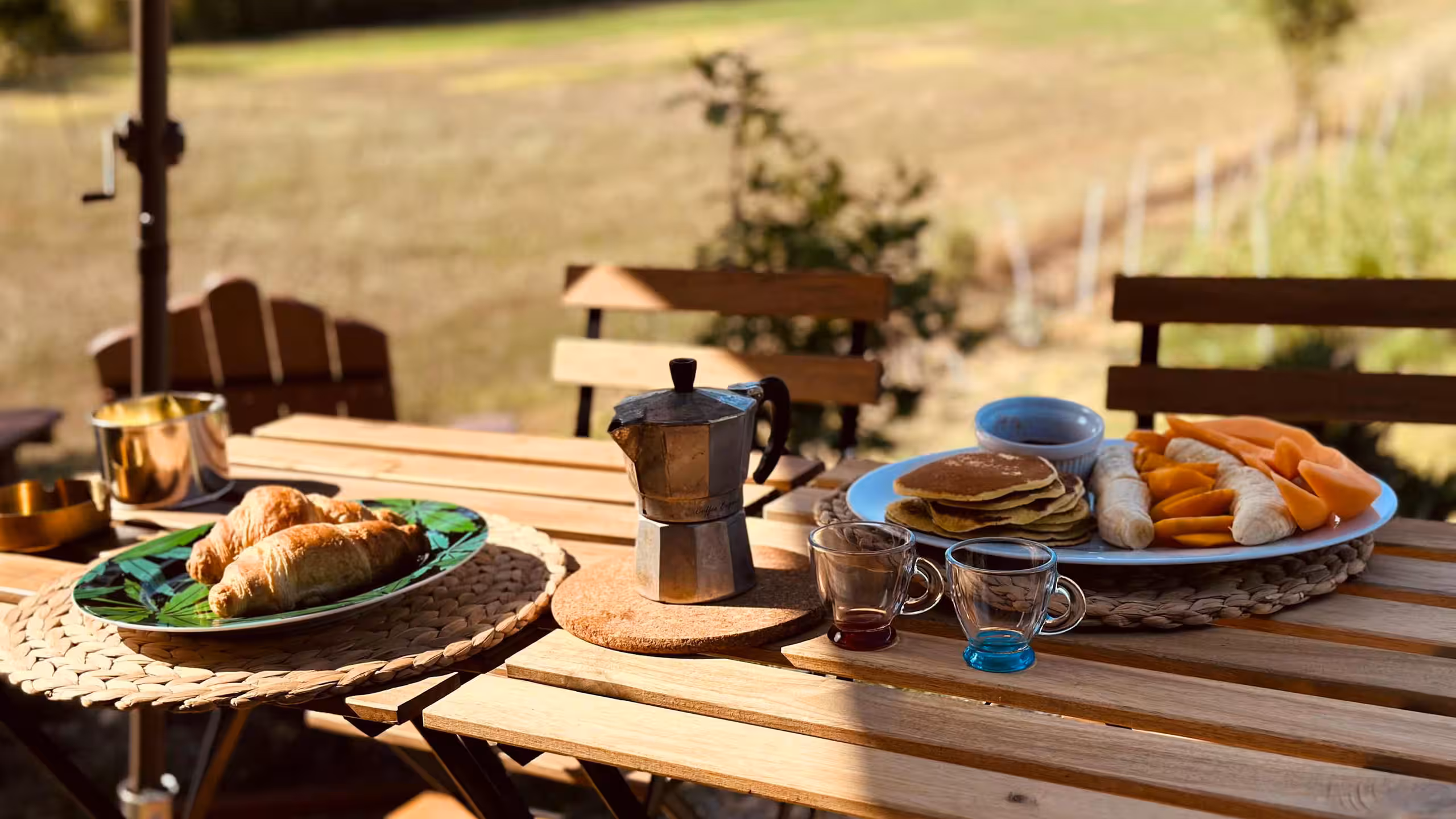 Colazione su un tavolo all'aperto: croissant, moka, pancake e frutta
