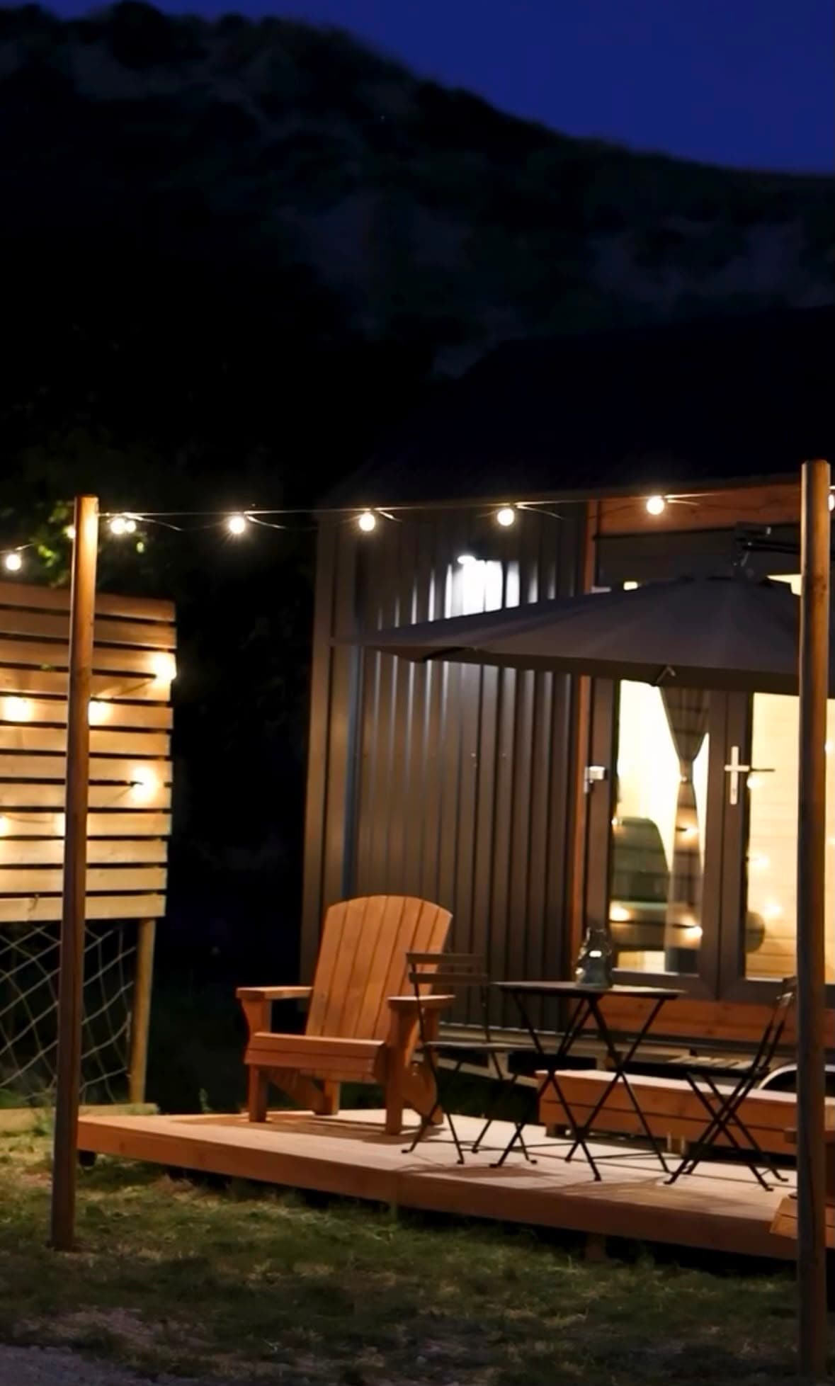 Il terrazzino della casetta di sera, con le luci accese e una sedia di legno